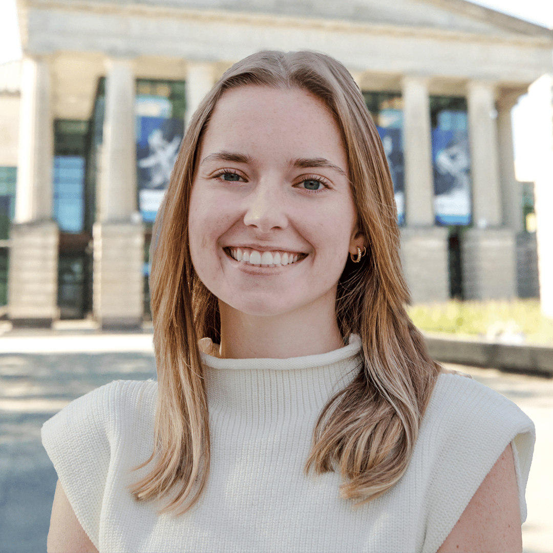 Headshot of Avery Vanore in front of the Martin Marietta Center for the Performing Arts wearing a white turtleneck sweater. 