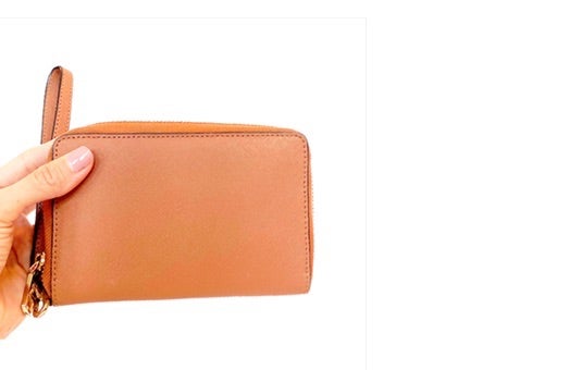 A photo of hand holding a small brown wallet