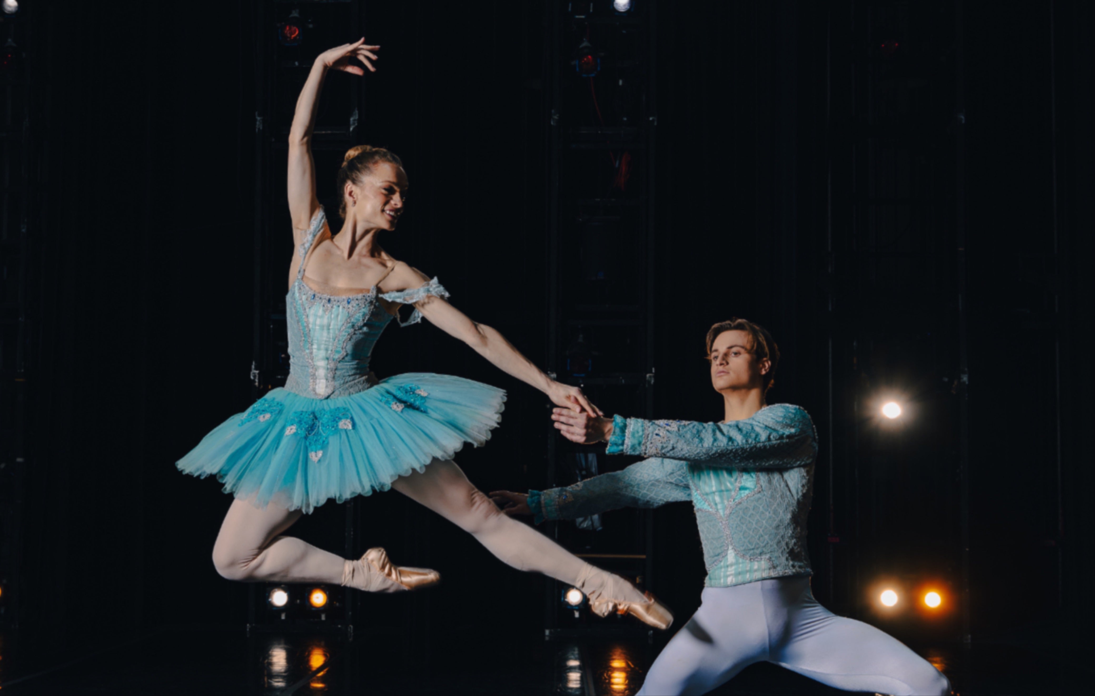 Two Ballet Dancers shown in blue costumes with their arms stretched out