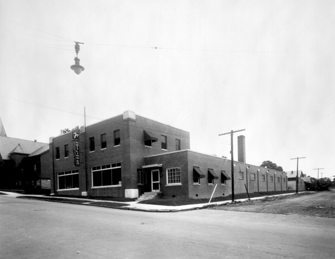 a black and white photo of the 7up bottling building it is a large two story brick building.