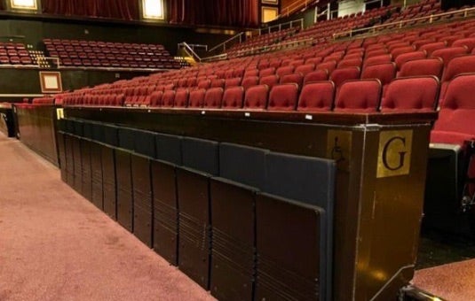 A photo of accessible seats in Raleigh Memorial Auditorium these seats are flat against a wall and fold down