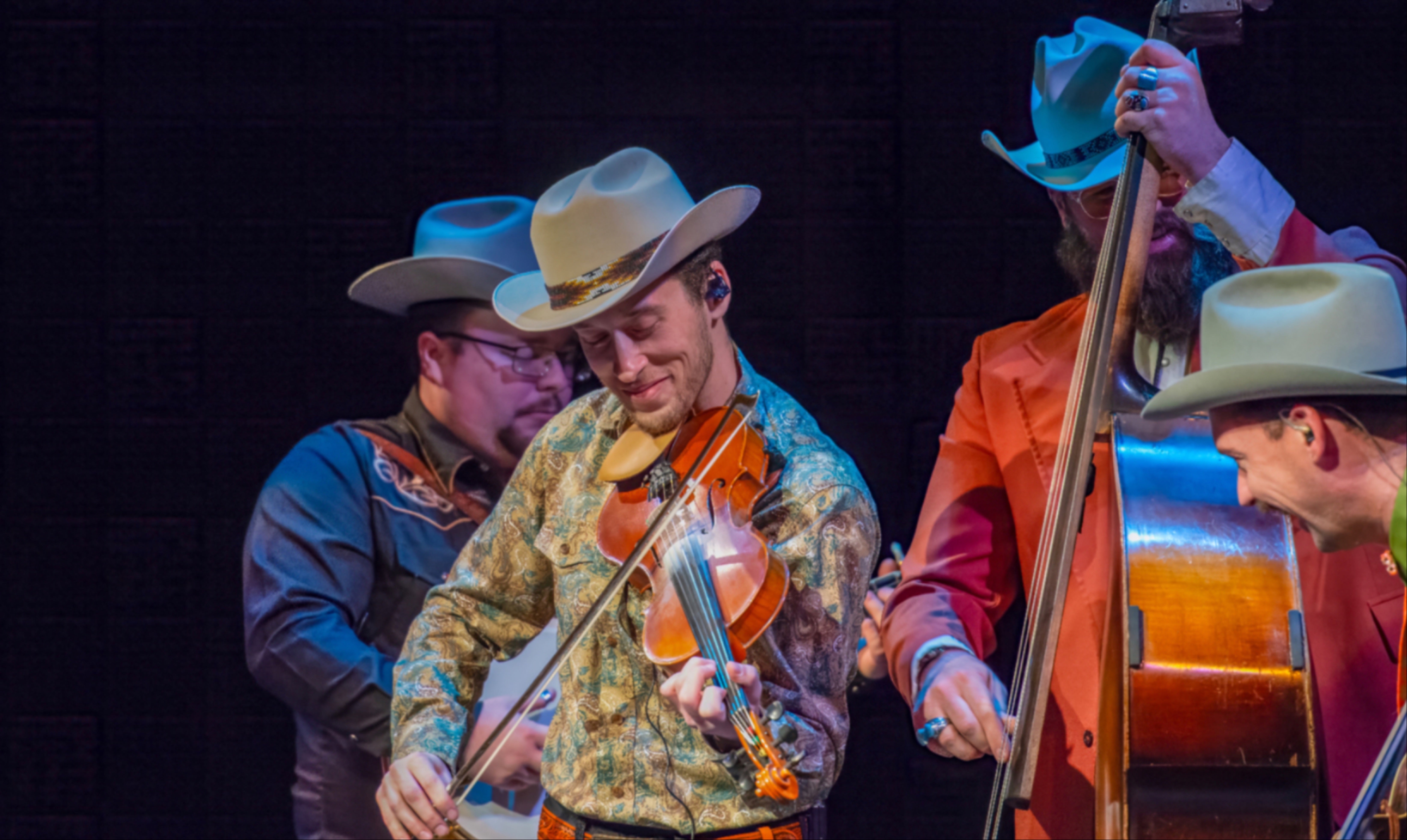 Performs from Po Ramblin Boys shown playing a fiddle he is wearing a hat