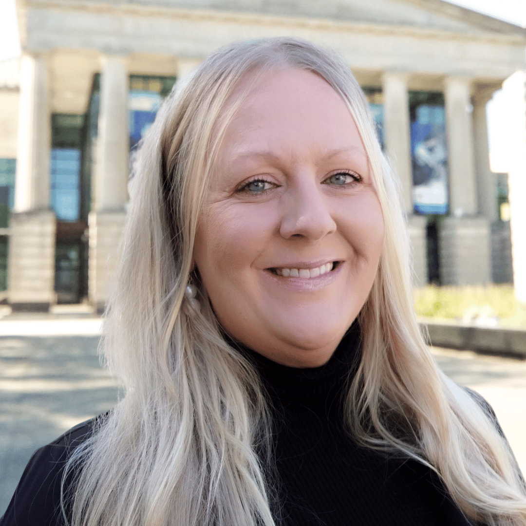 Headshot of Shelly Westfall outside the Martin Marietta Center for the Performing Arts wearing a black turtleneck sweater.