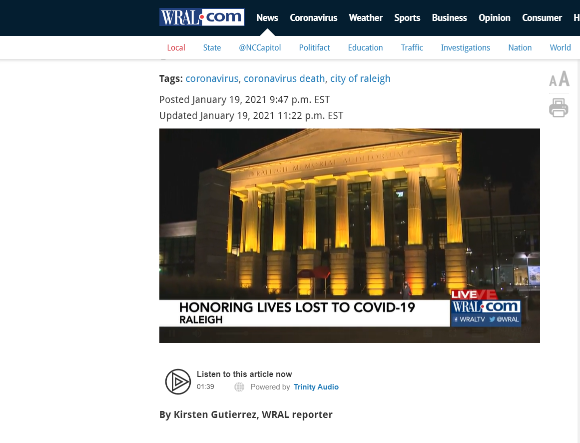 A screenshot of the wral.com news page showing a photo at the top of the raleigh memorial auditorium with amber lights on below that is additional text