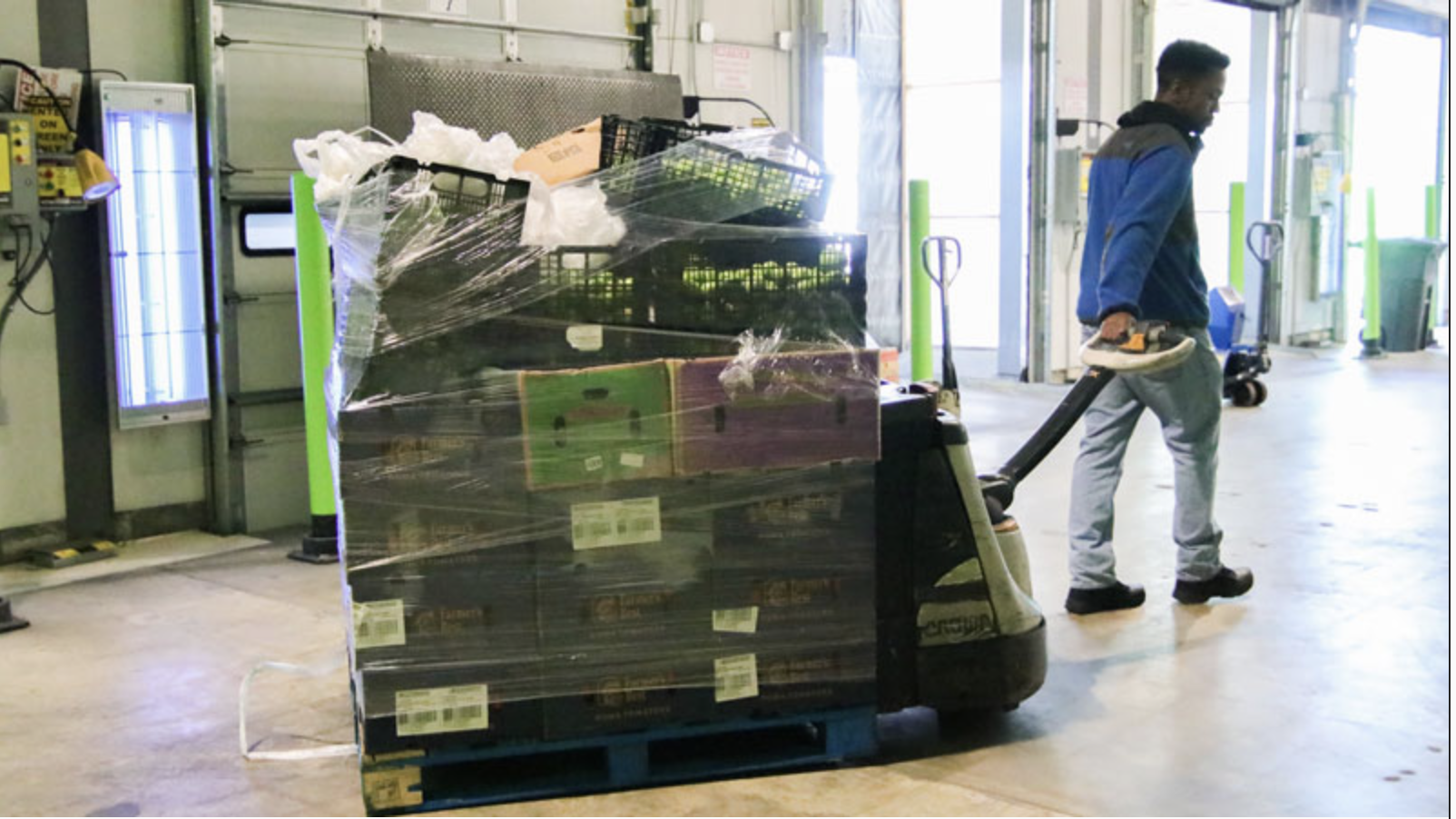 a photo showing a staff member pulling a pallet of food boxes wrapped in plastic