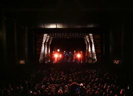 a view of the stage of Raleigh Memorial Auditorium from the audience showing a band on stage and two bright lights