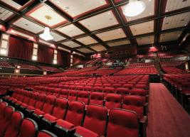 a view of the red seats of Raleigh Memorial Auditorium showing chandeliers