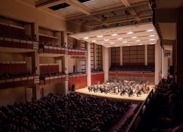 of view of the stage of Meymandi Concert Hall from the upper balcony boxes showing guests in seats and the NC Symphony on stage