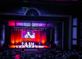 a view of the stage of Raleigh Memorial Auditorium from the audience showing a band on stage