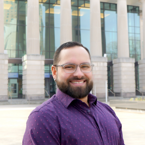 a photo of Andrew armas he is wearing glasses and has on a purple button down shirt