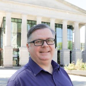 a photo of Gavin Brown he is wearing glasses and has on a purple button down shirt