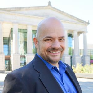 a photo of MATT HESTER he is wearing a blue button down and a dark navy sport coat