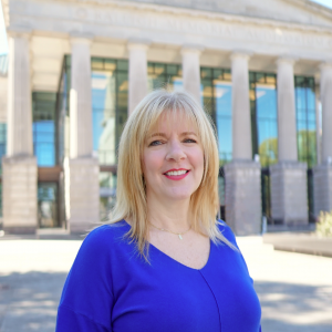 a photo of TAMI KAUFMANN she has shoulder length blonde hair and is wearing a bright blue blouse