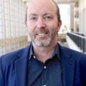 a photo of Jamie Jenkins he is wearing a blue button down shirt with a navy blue sport coat