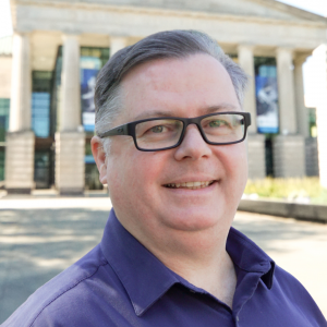 a photo of Gavin Brown he is wearing glasses and has on a purple button down shirt