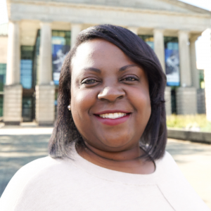 a photo of Keisha peacock she has brown shoulder length hair and is wearing a white blouse